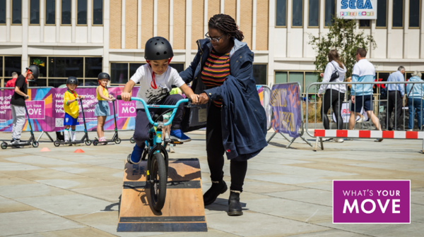 A Child On A Bike Is Helped Over A Ramp During A What's Your Move Session At Barnsley's Big Weekend