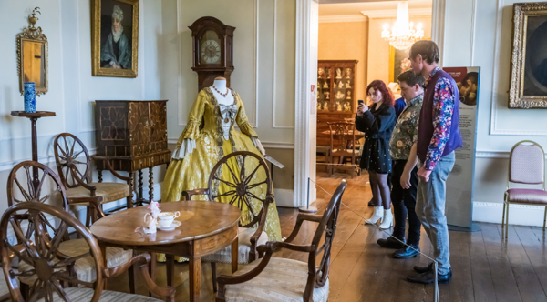 Three people looking at a yellow dress at Cannon Hall Museum, Park and Gardens