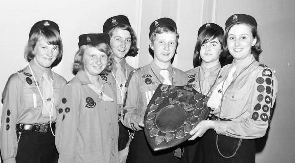 A photograph of girl guides holding a shield with awards on it