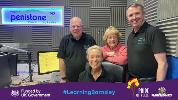 A Group Of People In A Radio Studio Under A Sign Reading Penistone FM