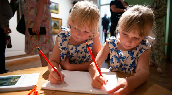 Two children drawing on a piece of paper at The Cooper Gallery